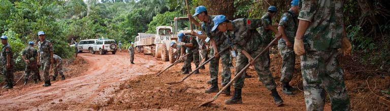 UN peacekeepers repairing a water damaged mud road.
